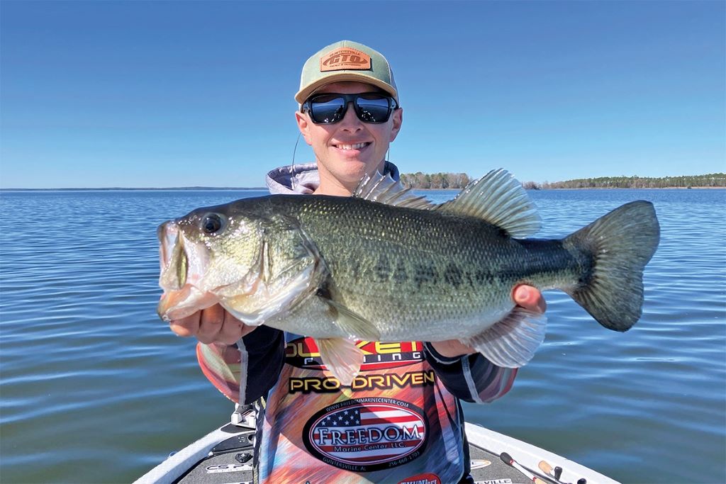 Angler casting a Carolina rig on a calm Canadian lake, aiming to catch bass near rocky structures