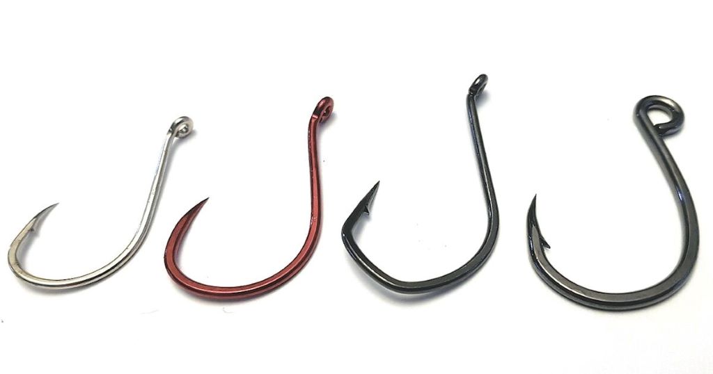 Close-up of three popular fishing hooks—Mustad, Gamakatsu, and VMC—displayed side by side for comparison at the Canadian Fishing Hook Showdown