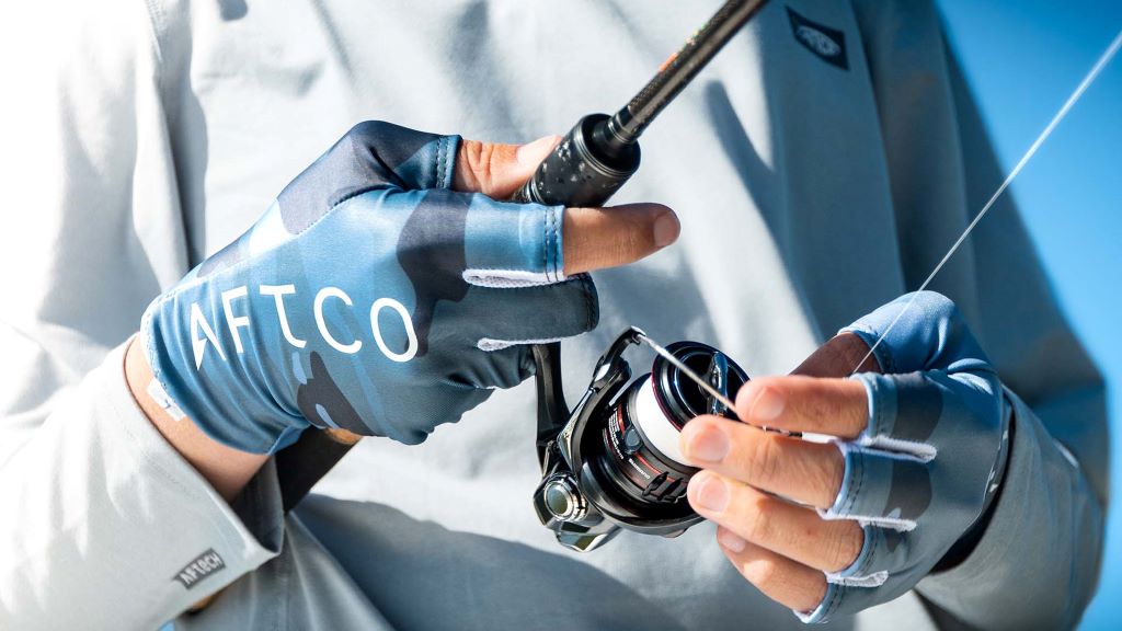 Angler wearing fishing gloves for better grip and hand protection while holding a fishing rod