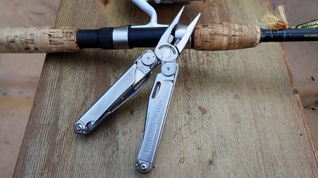 Angler using fishing pliers multitool to remove hook from fish on a fishing trip