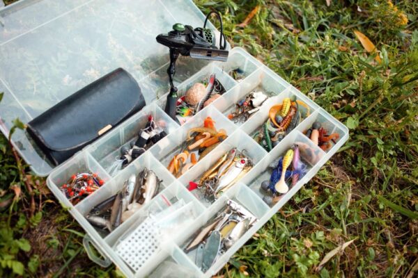 Angler neatly organizing fishing tackle box with lures, hooks, and fishing gear compartments