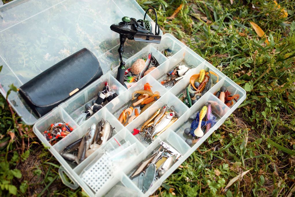 Angler neatly organizing fishing tackle box with lures, hooks, and fishing gear compartments